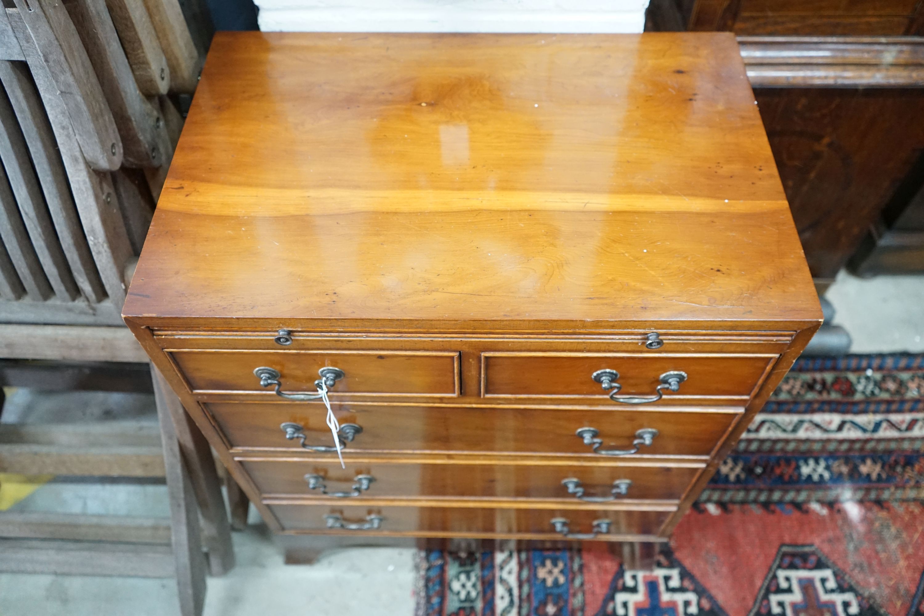 A small reproduction yew bachelor's chest of two short and three long drawers below brush slide, width 60cm, depth 40cm, height 74cm